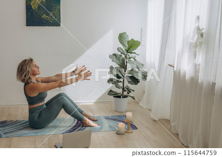 A 50-year-old woman does yoga at home 115644759