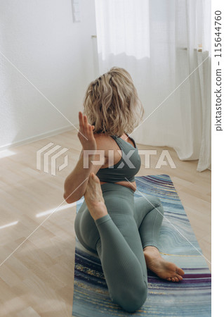 A 50-year-old woman does yoga at home 115644760