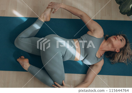 A 50-year-old woman does yoga at home A 50-year-old woman does yoga at home 115644764