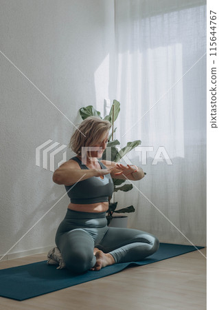 A 50-year-old woman does yoga at home A 50-year-old woman does yoga at home 115644767