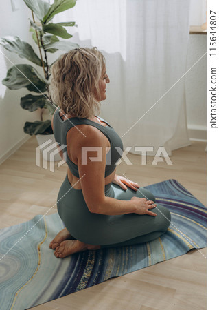 A 50-year-old woman does yoga at home 115644807