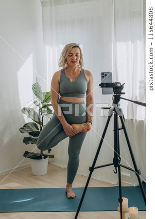 A 50-year-old woman doing online yoga at home 115644808