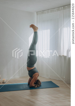 A 50-year-old woman does yoga at home 115644820