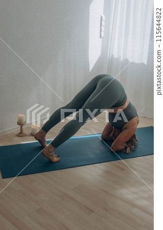 A 50-year-old woman does yoga at home 115644822