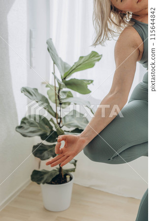 A 50-year-old woman does yoga at home 115644842