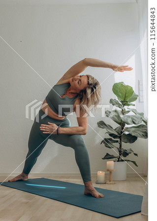 A 50-year-old woman does yoga at home 115644843