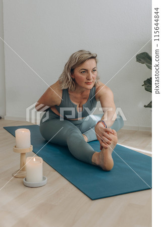 A 50-year-old woman does yoga at home 115644844