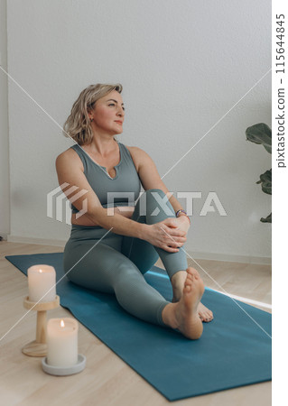 A 50-year-old woman does yoga at home 115644845