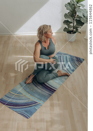 A 50-year-old woman does yoga at home 115644862