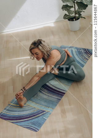 A 50-year-old woman does yoga at home 115644867