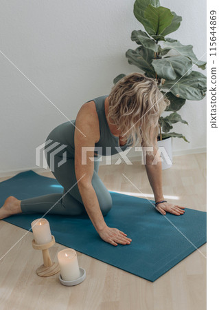 A 50-year-old woman does yoga at home 115644869