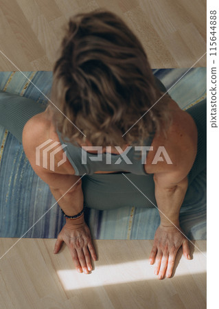 A 50-year-old woman does yoga at home A 50-year-old woman does yoga at home 115644888