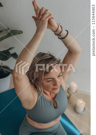 A 50-year-old woman does yoga at home 115644903