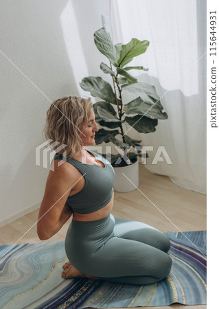 A 50-year-old woman does yoga at home A 50-year-old woman does yoga at home 115644931