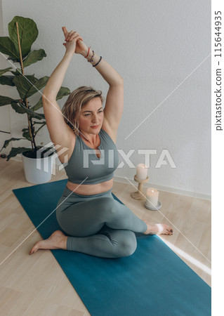 A 50-year-old woman does yoga at home 115644935