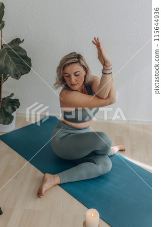 A 50-year-old woman does yoga at home 115644936