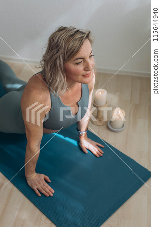 A 50-year-old woman does yoga at home 115644940