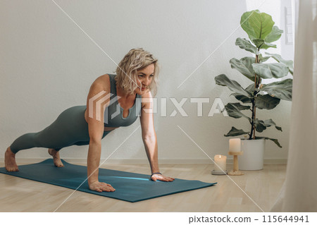 A 50-year-old woman does yoga at home 115644941