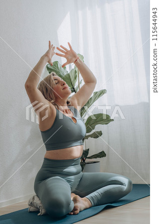 A 50-year-old woman does yoga at home 115644943