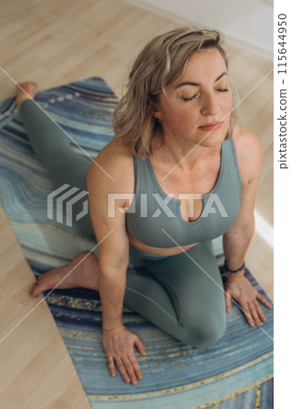 A 50-year-old woman does yoga at home A 50-year-old woman does yoga at home 115644950