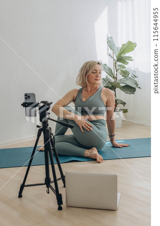 A 50-year-old woman doing online yoga at home 115644955