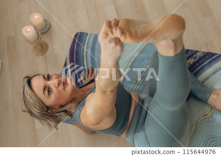 A 50-year-old woman does yoga at home 115644976