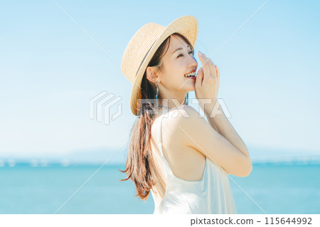 A woman wearing a straw hat with the sea and blue sky in the background A woman wearing a straw hat with the sea and blue sky in the background 115644992