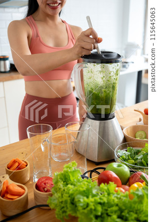A cropped image of a healthy woman in sportswear is making a healthy green smoothie with a blender. A cropped image of a healthy woman in sportswear is making a healthy green smoothie with a blender. 115645063