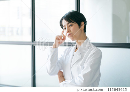 A woman in a white coat with a thinking expression 115645615