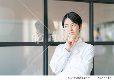 一個穿著白大褂的女人帶著思考的表情 一個穿著白大褂的女人帶著思考的表情 115645616
