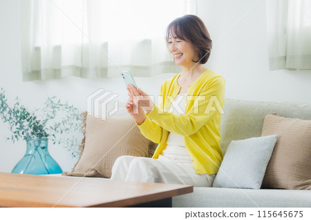 在客廳裡操作智能手機的中年女人 115645675
