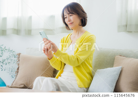 在客廳裡操作智能手機的中年女人 115645676
