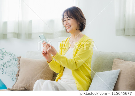 A middle woman who operates a smartphone in the living room 115645677