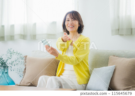 A middle woman who operates a smartphone in the living room A middle woman who operates a smartphone in the living room 115645679
