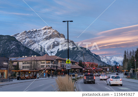 Street view of Banff Avenue in autumn evening. Snow capped Cascade Mountain with pink rosy sky in the background. Alberta, Canada. Street view of Banff Avenue in autumn evening. Snow capped Cascade Mountain with pink rosy sky in the background. Alberta, Canada. 115645927