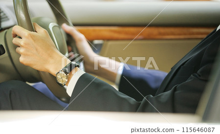 A young man in a suit holding a steering wheel 115646087