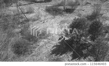 Men Dressed As US American Soldiers Of USA Infantry Of World War II open fire shooting mortar In spring Autumn Day. Soldiers shots mortar during battle In dry grass. Aerial view elevated shot 115646403