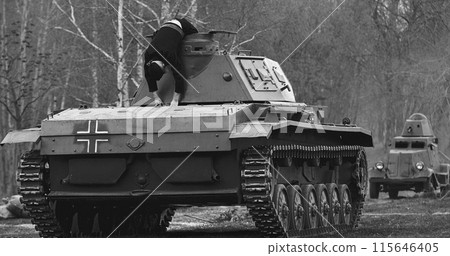 Re-enactor Dressed As Dead German Tank Crew Lies Slain on German Wehrmacht Light Panzer Tank In Reconstruction Of Battles World War Ii. After Battle. Black And White Re-enactor Dressed As Dead German Tank Crew Lies Slain on German Wehrmacht Light Panzer Tank In Reconstruction Of Battles World War Ii. After Battle. Black And White 115646405