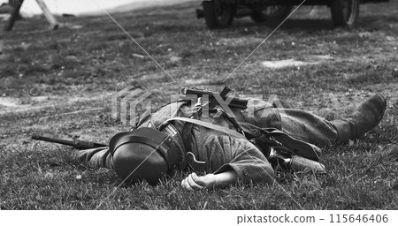 Re-enactor Dressed As German Wehrmacht Soldier Lies Slain In Reconstruction Of Battles World War Ii. German Infantry Soldier In World War Ii. Reconstruction. Black And White 115646406