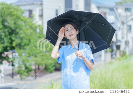 Woman with a parasol (UV protection, sunscreen, UV care, heat stroke protection, sun allergy, poor physical condition) 115646421