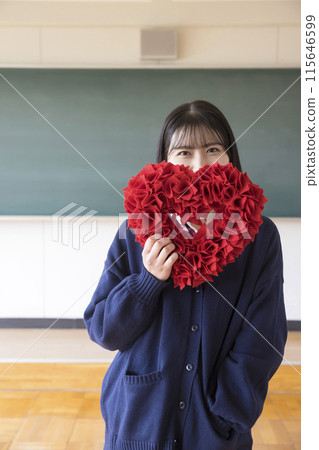 High school girl holding a heart in the classroom 115646599
