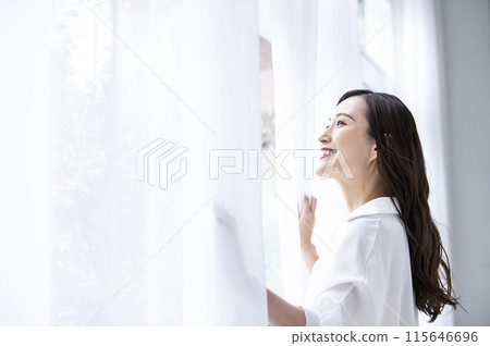 A young woman who opens a curtain 115646696