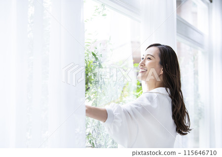 A young woman who opens a curtain 115646710