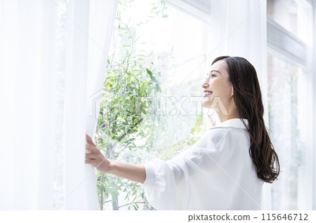 A young woman who opens a curtain 115646712