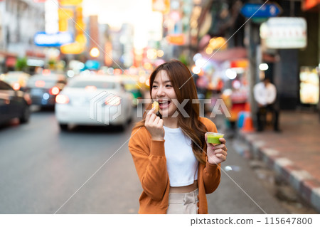 Young Asian tourists standing and eating Thai desserts 115647800