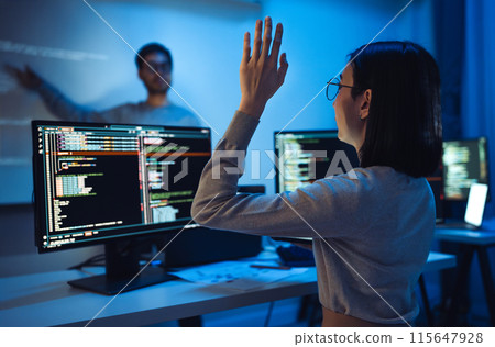 trainee developer hand up to ask speaker about software coding project presentation at night in office 115647928