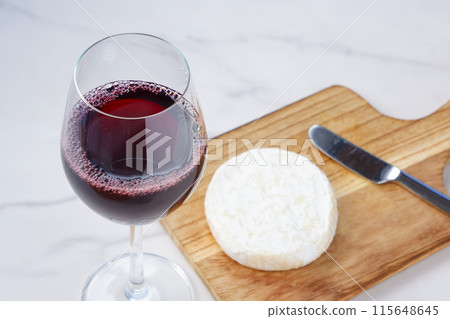 Red wine poured into a wine glass and Camembert cheese as an appetizer Red wine poured into a wine glass and Camembert cheese as an appetizer 115648645