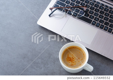 Image of a man working at his desk on a laptop while drinking a delicious cafe latte Image of a man working at his desk on a laptop while drinking a delicious cafe latte 115649332