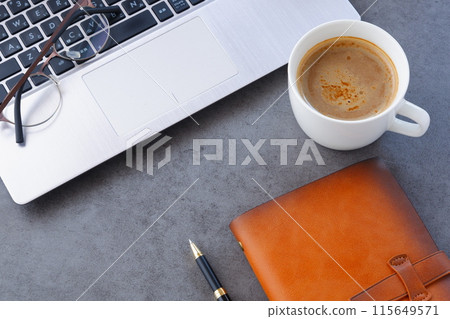 An image of someone working at a desk with a laptop and a personal organizer while drinking freshly brewed coffee An image of someone working at a desk with a laptop and a personal organizer while drinking freshly brewed coffee 115649571