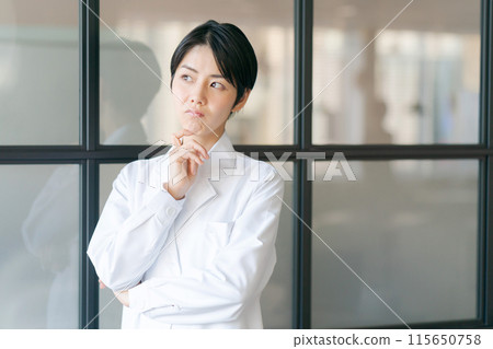A worried woman in a white coat 115650758